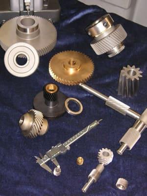 Helical gears, worm shafts and splined components on the bench.